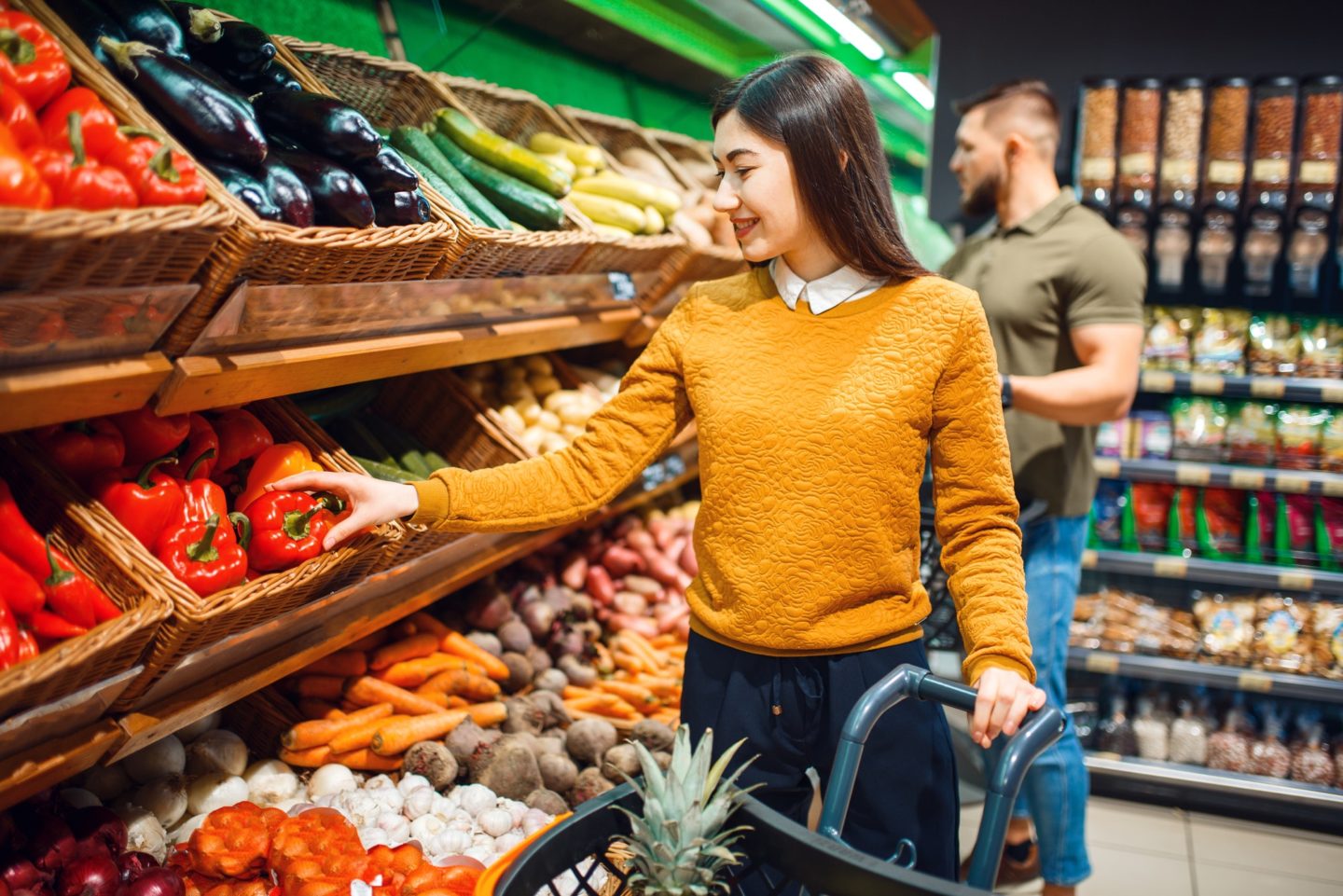 Happy couple with basket in grocery store